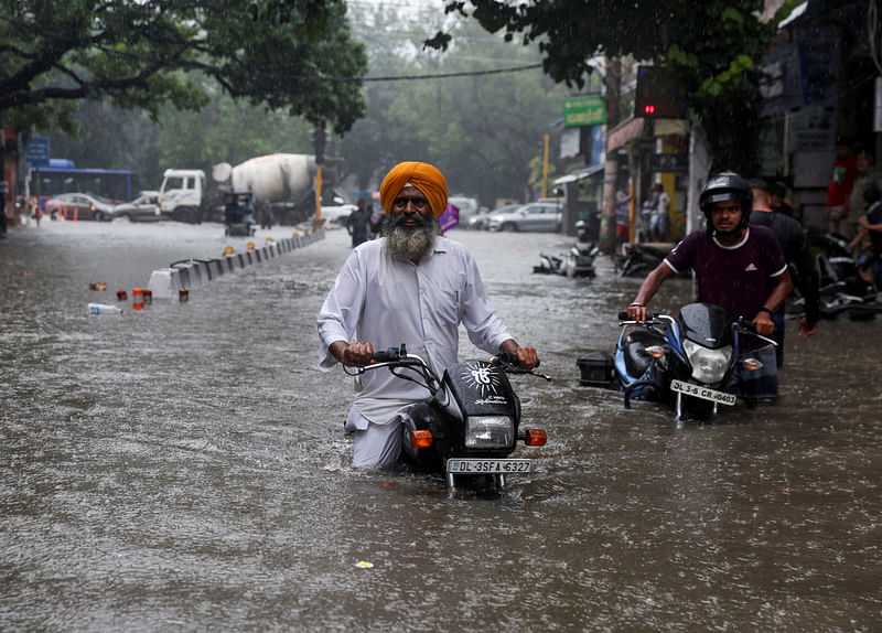 A man on his motorbike wades through a flooded street after heavy rains in New Delhi, India, 8 July 2023.