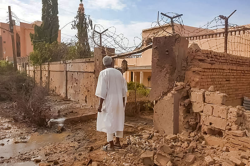 A man walks through rubble by a bullet-riddled fence with barbed-wire, in the aftermath of clashes and bombardment in the Ombada suburb on the western outskirts of Omdurman, the twin-city of Sudan's capital, on 4 July, 2023