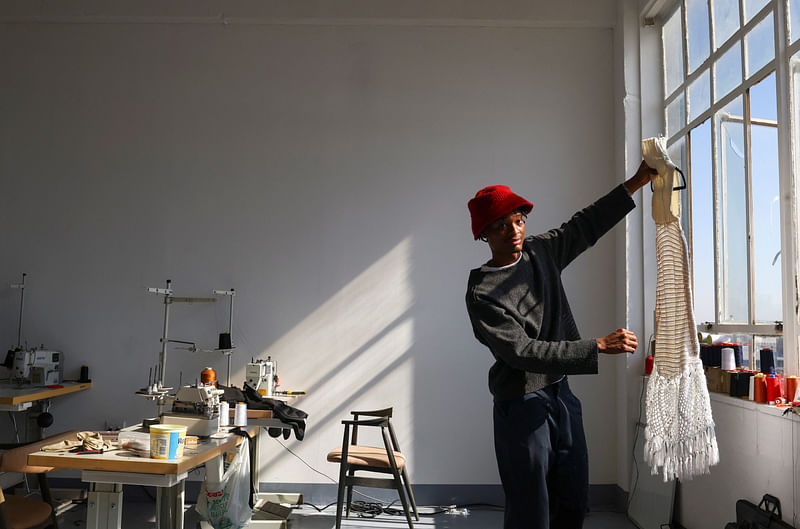 South African aspiring designer Khumo Morojele inspects a second hand clothing imported from the West and sold in bales in markets known as Dunusa, at his studio, in Johannesburg South Africa, 3 July, 2023.