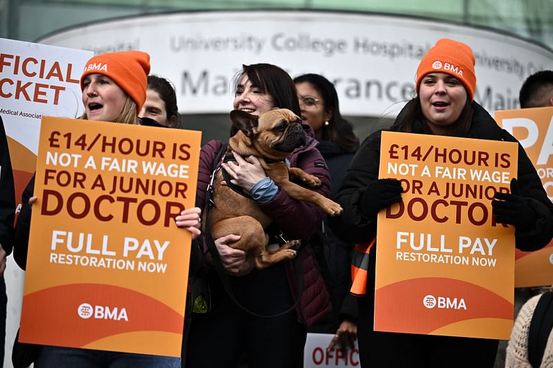 People hold British Medical Association (BMA) branded placards calling for better pay, as they stand on a picket line outside University College Hospital (UCH) in central London on April 12, 2023, during a strike by junior doctors -- physicians who are not senior specialists but who may still years of experience