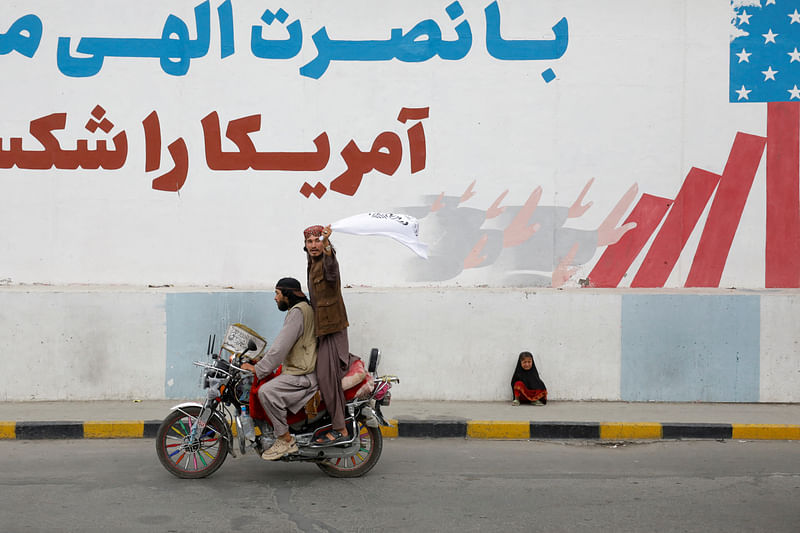 A Taliban supporter holds an Islamic Emirate of Afghanistan flag on the first anniversary of the fall of Kabul on a street in Kabul, Afghanistan, August 15, 2022