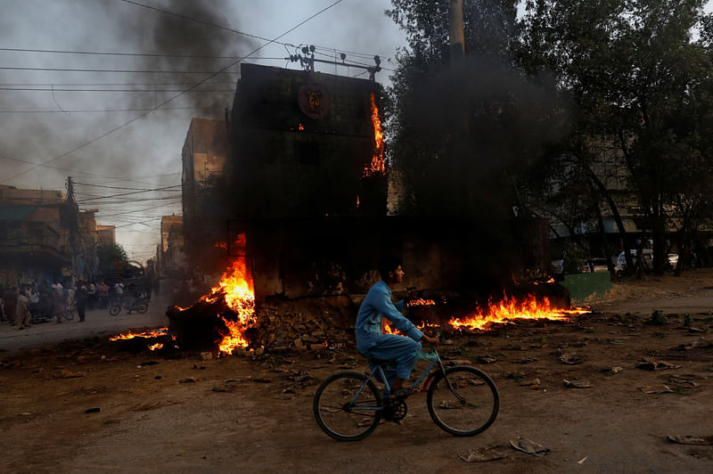 A boy rides past a paramilitary check post, that was set afire by the supporters of Pakistan's former Prime Minister Imran Khan, during a protest against his arrest, in Karachi, Pakistan, May 9.