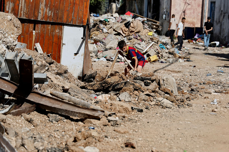 A Palestinian boy clears the rubble of the destroyed road in front of his house following an Israeli military operation, in Jenin camp in the Israeli-occupied West Bank July 6, 2023