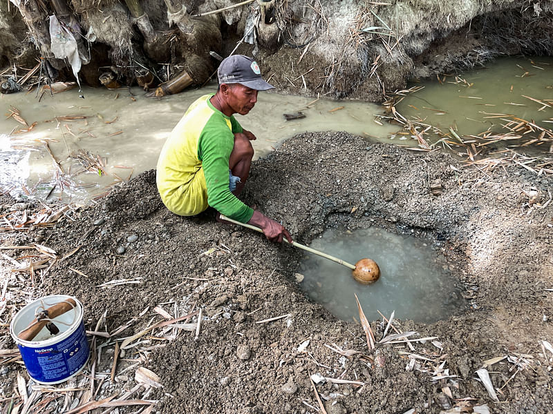 Sunardi, a 52-year-old tobacco farmer, collects murky water for daily needs from a hand-dug well on a dry riverbed, the only remainder of what was once a flowing river as drought strikes in Grobogan regency, Central Java province, Indonesia, July 27, 2023.