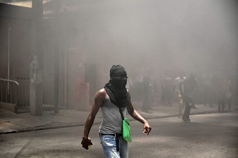 A man walks through smoking tires during a demonstration against insecurity in Port-au-Prince, Haiti, on 14 August, 2023.