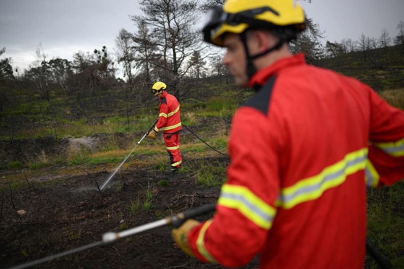 Firefighters from the Surrey Fire and Rescue Service use small pressure hoses used to extinguish small fires during a press preview at Hankley Common, the site of a wildfire during a heatwave in 2022, in Surrey, southeast England, on 24 August, 2023