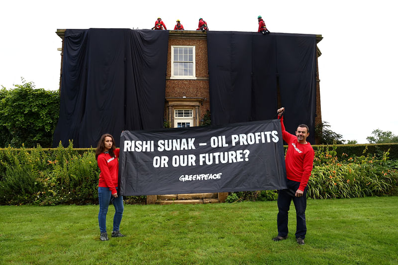 Greenpeace activists hold a banner while others cover British Prime Minister Rishi Sunak's £2m manor house in oil-black fabric in protest of his backing for a major expansion of North Sea oil and gas drilling amidst a summer of escalating climate impacts, in Yorkshire, Britain on 3 August, 2023.