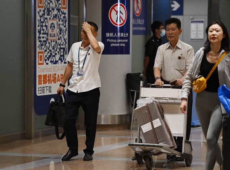 Two North Korean men (L and 2nd R) walk through the arrivals section at Beijing Capital Airport after the arrival of Air Koryo flight JS151 on August 22, 2023