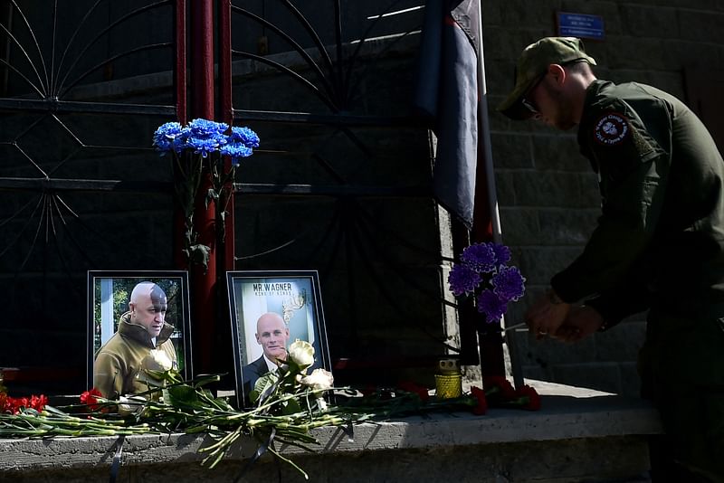 A member of private mercenary group Wagner pays tribute to Yevgeny Prigozhin (L) and Dmitry Utkin, a shadowy figure who managed Wagner's operations and allegedly served in Russian military intelligence, at the makeshift memorial in front of the PMC Wagner office in Novosibirsk, on 24 August, 2023.