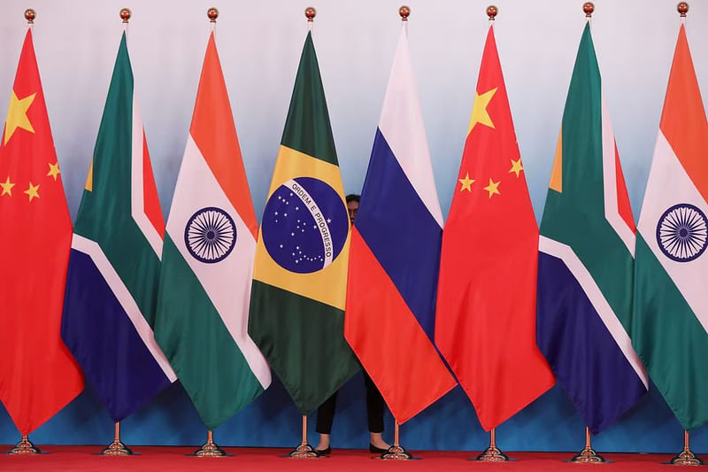 A staff worker stands behind the national flags of Brazil, Russia, China, South Africa and India to tidy the flags before a group photo during the BRICS Summit at the Xiamen International Conference and Exhibition Center in Xiamen, southeastern China's Fujian Province, China on 4 September, 2017.