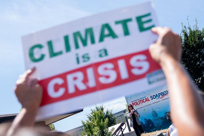 An attendee holds a "Climate is a Crisis" sign as Marianne Williamson, 2024 Presidential hopeful, speaks at the Des Moines Register Political Soapbox at the Iowa State Fair in Des Moines, Iowa, on August 12, 2023