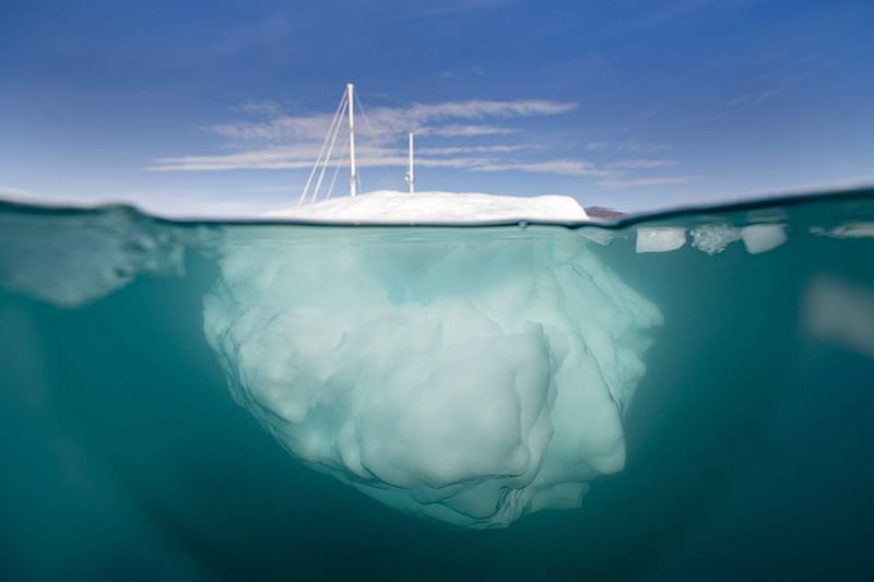 The Greenlandia expedition's sailing boat 'Kamak' sails between icebergs released by glaciers around Milne Land in the Scoresby Sound Fjord, Eastern Greenland on August 15, 2023.