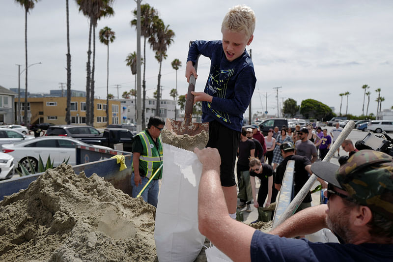 Bradford Slevin and his eight-year-old son, Theo, fill up sandbags to take home as Hurricane Hilary approaches in Long Beach, California, U.S. August 19, 2023