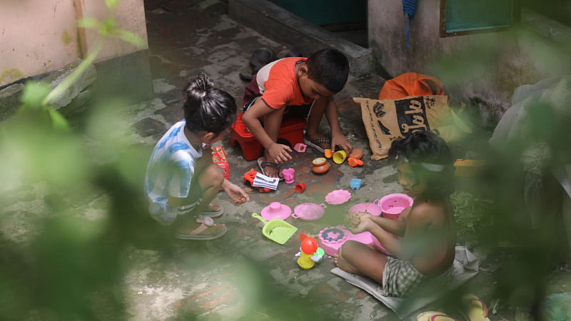 Children play with their kitchen sets in the yard in the Deobhog area of Akhra, Narayanganj.