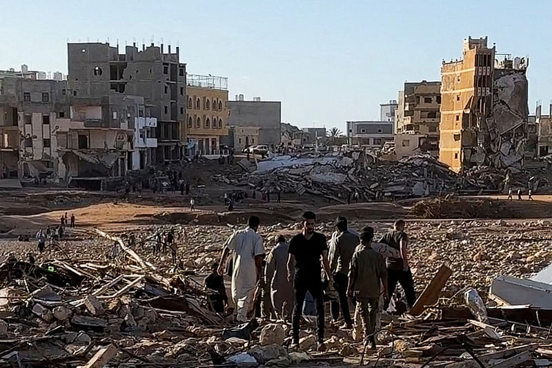 People walk through debris after a powerful storm and heavy rainfall hit Libya, in Derna, Libya, on 12 September, 2023 in this still image from video obtained from social media