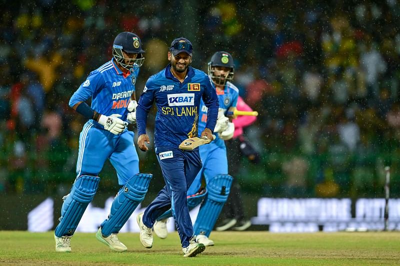 Sri Lanka's Dimuth Karunaratne (c), India's Axar Patel (L) and Mohammed Siraj leave the field as rain stops play during the Asia Cup 2023 Super Four one-day international (ODI) cricket match between India and Sri Lanka at the R. Premadasa Stadium in Colombo on 12 September, 2023