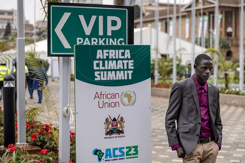 A delegate stands in front of a placard with an Africa Climate Summit logo as he waits to access the venue ahead of the Africa Climate Summit 2023 at the Kenyatta International Convention Centre in Nairobi, Kenya on September 2, 2023