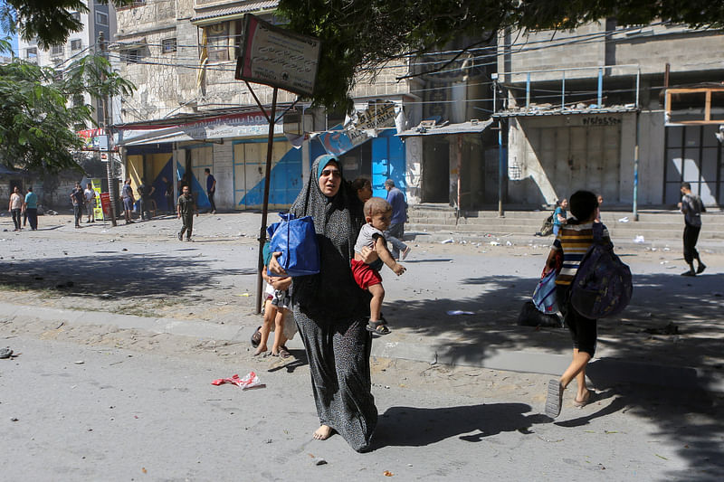 Palestinians run on a street following Israeli strikes in Gaza City October 15, 2023