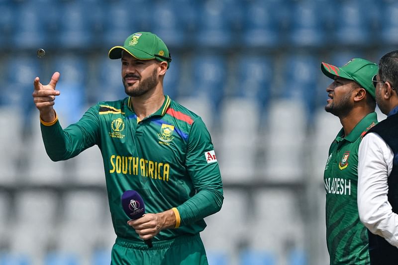 South Africa's captain Aiden Markram (L) tosses the coin as his Bangladesh's counterpart Shakib Al Hasan (C) watches before the start of the 2023 ICC Men's Cricket World Cup one-day international (ODI) match between South Africa and Bangladesh at the Wankhede Stadium in Mumbai on October 24, 2023.