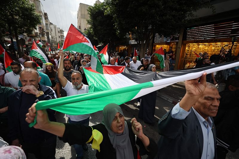 People wave Palestinian flags as they demonstrate against Israel in the streets of the occupied West Bank city of Ramallah on 19 October, 2023