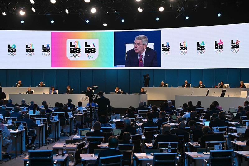 The International Olympic Committee (IOC) President Thomas Bach is seen on a digital screen as he speaks during the second day of the 141st session of the IOC in Mumbai on October 16, 2023. Cricket will feature as one of five new sports at the 2028 Olympic Games in Los Angeles, organisers announced on 16 October, 2023