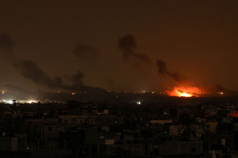 This picture taken from Rafah, shows smoke and fire rising above buildings during Israeli strikes on eastern Khan Yunis in the southern Gaza Strip on 22 November, 2023