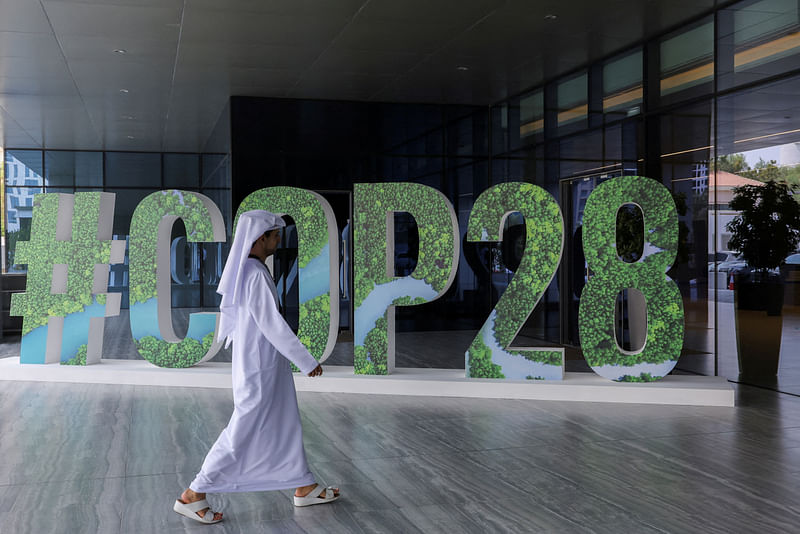 A person walks past a '#COP28' sign during The Changemaker Majlis, a one-day CEO-level thought leadership workshop focused on climate action, in Abu Dhabi, United Arab Emirates, 1 October, 2023.