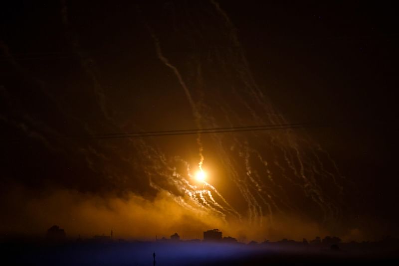 This picture taken from the Israeli side of the border with Gaza shows smoke and flares dropped by Israeli forces over the Gaza Strip on 10 November, 2023