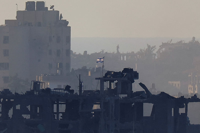 An Israeli flag flutters on a destroyed building in Gaza, as seen from southern Israel, amid the ongoing conflict between Israel and the Palestinian group Hamas, November 18, 2023