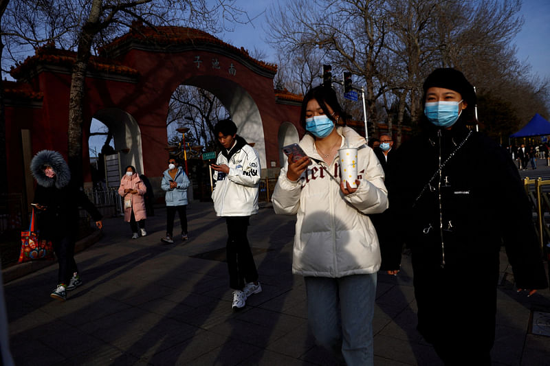 People, wearing masks to prevent coronavirus disease (COVID-19), walk along the street in Beijing, China, February 14, 2023