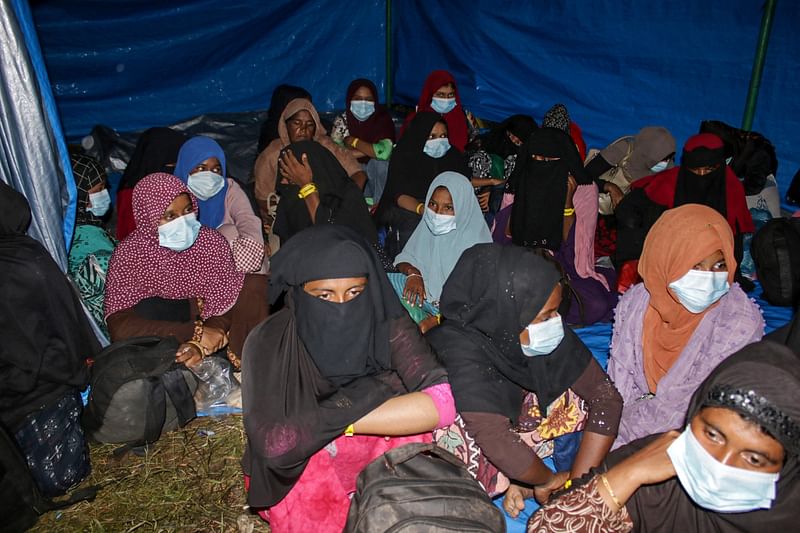 Rohingya women refugees await a vehicle as Indonesian authorities relocate them to an immigration building, in Lapang Barat village, Bireuen, Aceh province on 21 November, 2023