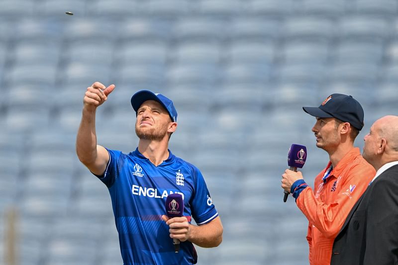 England's captain Jos Buttler (L) tosses the coin as his Netherlands' counterpart Scott Edwards (2R) watches before the start of the 2023 ICC Men's Cricket World Cup one-day international (ODI) match between England and Netherlands at the Maharashtra Cricket Association Stadium in Pune on 8 November, 2023.