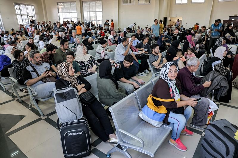 People sit in the waiting area at the Rafah border crossing in the southern Gaza Strip before crossing into Egypt on November 1, 2023