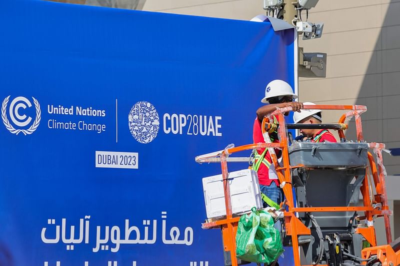 Workers install a COP28 sign on the eve of the United Nations climate summit in Dubai on 29 November 2023. The central focus of the 30 November to 12 December COP28 talks will be a damning stocktaking of the world's limited progress on cutting greenhouse gas emissions.