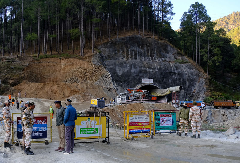 Police officers stand guard next to a barricade past the entrance of a tunnel where 40 road workers are trapped after a portion of the tunnel collapsed in Uttarkashi in the northern state of Uttarakhand, India, November 16, 2023