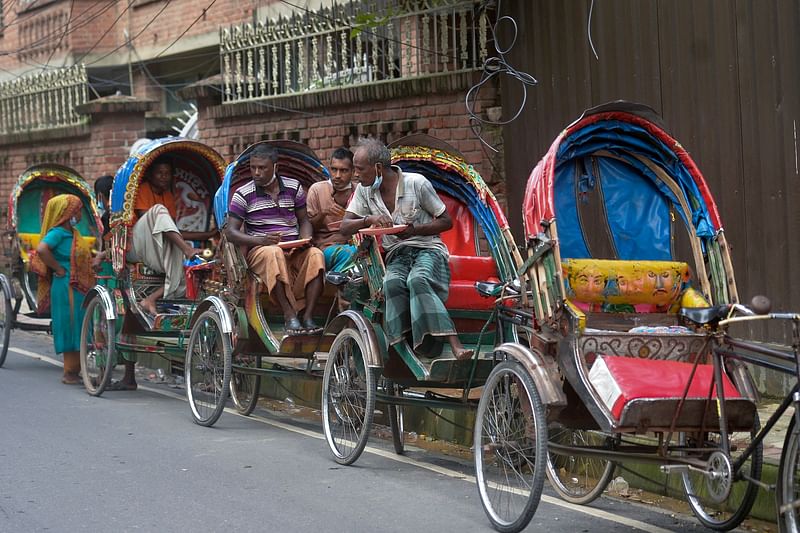 Rickshaw pullers eat food distributed by the non-profit organization Mehmankhana during nationwide lockdown imposed to curb the spread the Covid-19 coronavirus in Lalmatia area of Dhaka on 7 July, 2021