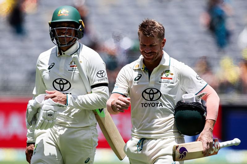 David Warner (R) and teammate Usman Khawaja leave at the lunch break during a test cricket match in Perth on 14 December, 2023.