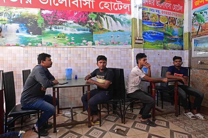 In this photograph taken on 13 November, 2023, Naim Pramanik (2L), a garment worker who lost his job, sits along with union leader Prodip Ray (L) at a restaurant in Dhaka. For a decade, the nimble fingers of Bangladeshi garment worker Naim Pramanik sewed shirts and trousers for top Western brands, to be worn by the wealthy across the world. Now the 28-year-old is unemployed, sacked after daring to take part in protests demanding a fair wage