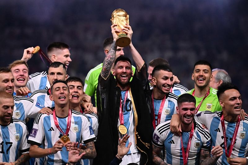 Argentina’s captain and forward #10 Lionel Messi (C) lifts the FIFA World Cup Trophy on stage as he celebrates with teammates after they won the Qatar 2022 World Cup final football match between Argentina and France at Lusail Stadium in Lusail, north of Doha on 18 December, 2022