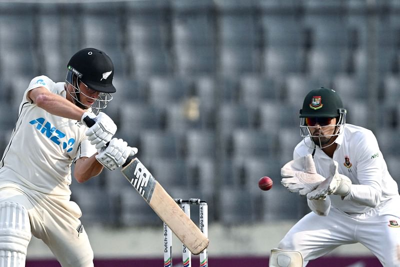 New Zealand's Mitchell Santner plays a shot as the Bangladesh's Nurul Hasan (R) watches during the fourth day of the second Test cricket match between Bangladesh and New Zealand at the Sher-e-Bangla National Cricket Stadium in Dhaka on 9 December, 2023.