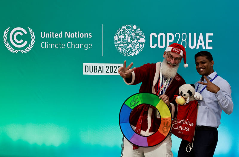 An observer dressed as Santa Claus gestures as he poses for a photo, at the United Nations Climate Change Conference COP28 in Dubai, United Arab Emirates, 11 December 2023.