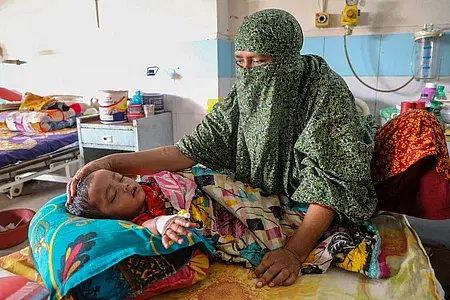 Kanchan Mala is trying to comfort his 18-month-old grandson Abu Sayeed, who has been diagnosed with dengue, at the Mugda General Hospital in the capital on Tuesday