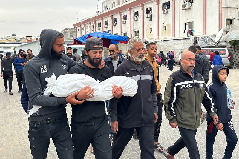 A Palestinian man carries the body of his daughter, Nisreen, as he prepares for her burial after she died as a result of injuries sustained following Israeli shelling near Khan Yunis on 22 December, 2023