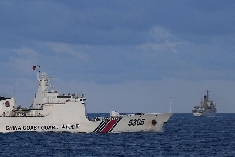 A Chinese Coast Guard ship sails near a Philippine vessel (R) that was part of a convoy of civilian boats in the disputed South China Sea on 10 December, 2023