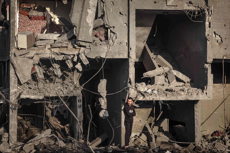 A Palestinian man stands in front of a building destroyed during Israeli bombardment around the town city of Rafah southern Gaza Strip on 24 January, 2024, amid ongoing battles between Israel and the Palestinian militant group Hamas