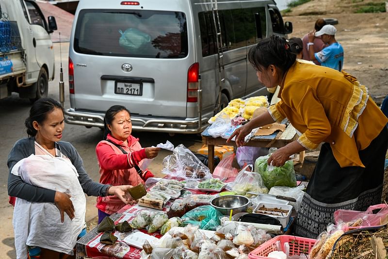 Women buy food from a vendor at a port along the Mekong river in Luang Prabang on 30 January , 2024.