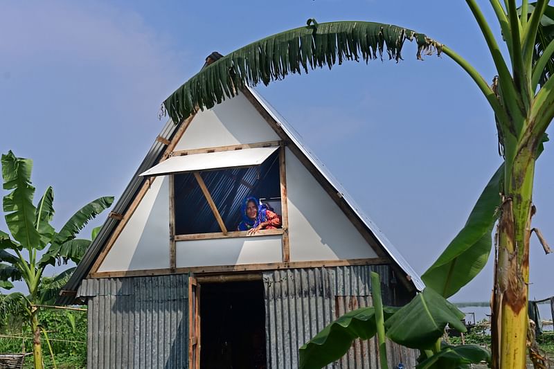 In this photograph taken on September 3, 2023, a woman looks outside a window as she sits on the loft of "Khudi Bari" or "tiny house", a mobile modular shelter, in Char Shildaha. An award-winning architect in Bangladesh, one of the nations most at risk from flooding driven by climate change, has developed an ingenious two-story housing solution to help people survive what scientists warn is a growing threat.