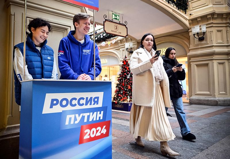 People walk past an election campaign stand of Russian President Vladimir Putin for collecting signatures to support him as a candidate for the upcoming presidential election, at the GUM department store in Moscow, on 19 January, 2024