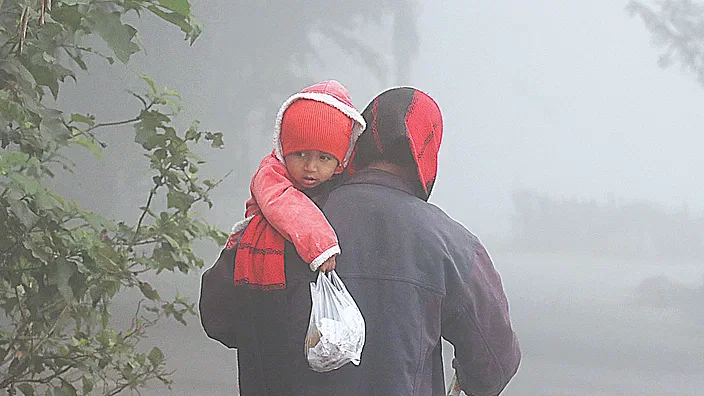 A man is carrying his child home from the market amidst the dense fog in the Jalchhatra area of in Rangpur suburbs.