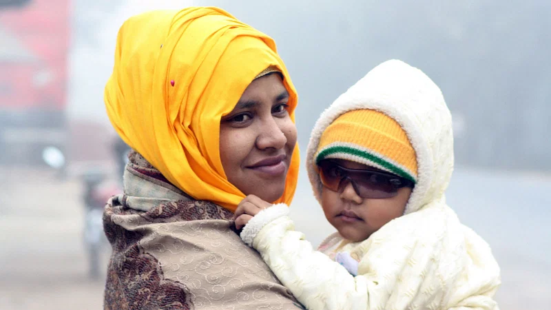 A mother wraps he child in warm clothes. photo taken from CO Bazar in Rangpur.